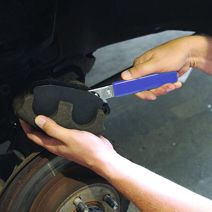Person using a brake pad thickness gauge on a car brake pad.