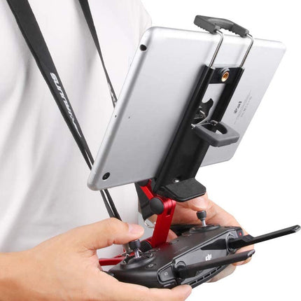 A close-up of a person holding a black drone remote controller with a tablet mounted on a red and black bracket, against a plain white background.