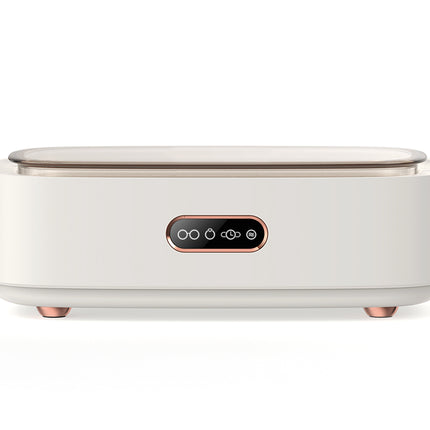 A modern, minimalist white countertop appliance with a flat top, small feet, and a central black control panel with rose gold accents, shown on a white background.