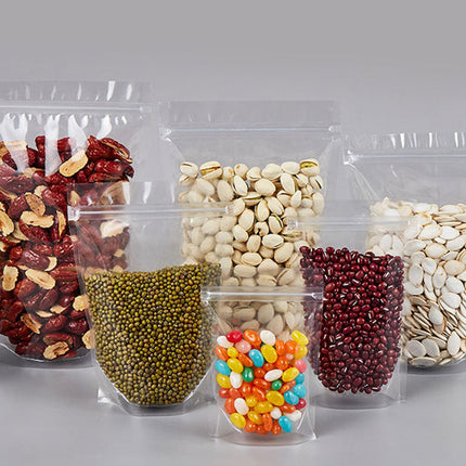 Clear plastic packaging bags filled with various types of nuts and seeds on a gray background