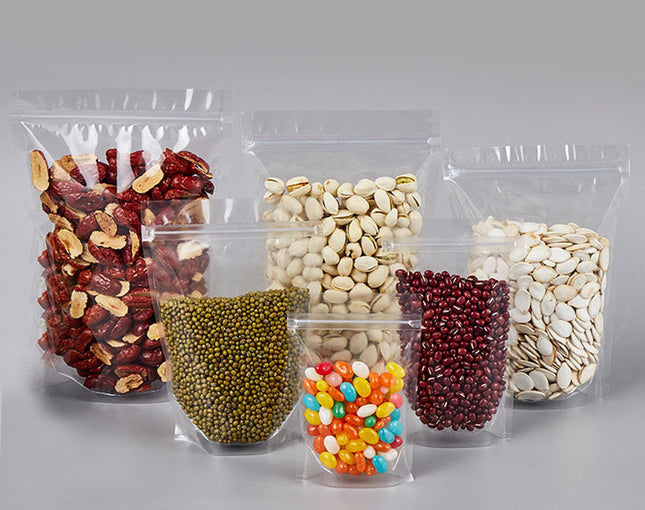 Clear plastic packaging bags filled with various types of nuts and seeds on a gray background