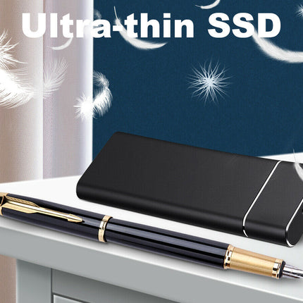 Black ultra-thin SSD next to a pen on a surface with a starry night background