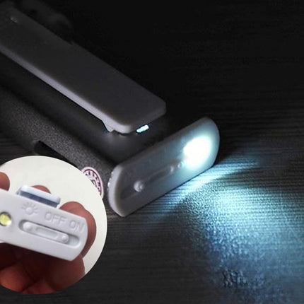 Small flashlight attached to a belt with a close-up of the switch on a dark background