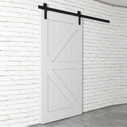 White barn door with black hardware on a white paneled wall.