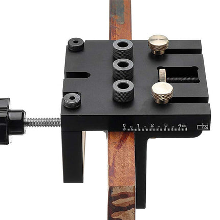 Black tool with adjustable components on a wooden stick against a white background