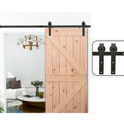Wooden sliding barn door with black hardware in a room setting.