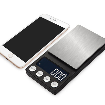 Digital pocket scale next to a smartphone on a white background