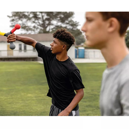 Two young men on a grassy field, one holding a colorful object.