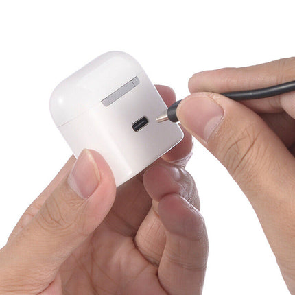 Person holding a white electronic device with a small black cable connector.