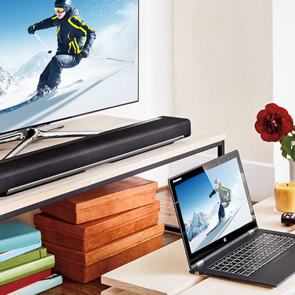 Living room setup with TV, soundbar, laptop, and decorative items.