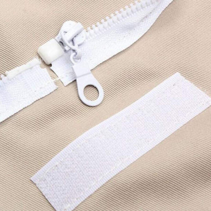 Close-up of a white zipper with a pull tab on a beige fabric background