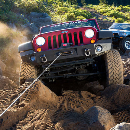 Red Jeep Wrangler on a rocky trail with another vehicle in the background