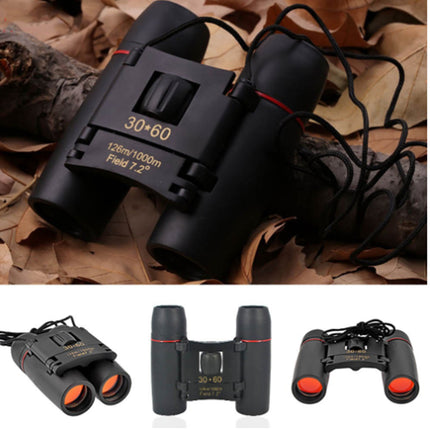 Black binoculars with red accents on a leafy background