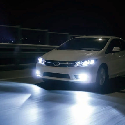 White car with bright headlights on a dark road