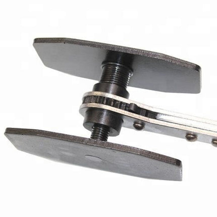 Close-up of a mechanical device with metal plates and a central screw on a white background