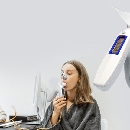 Woman using a handheld device with a screen, possibly for medical or diagnostic purposes, in an office setting.