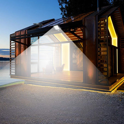 Modern cabin by a lake with a warm glow from interior lights.