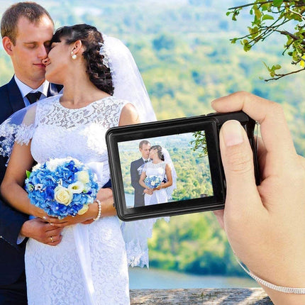 Hand holding a digital camera showing a wedding photo of a couple with a scenic background.