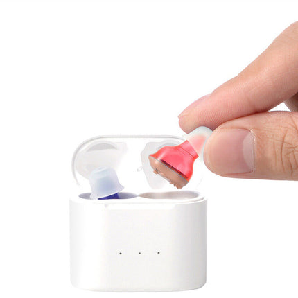 Hand placing a pink earbud into a white charging case on a white background