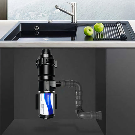 Under-sink plumbing system in a kitchen setting with a sink and apples on the counter.