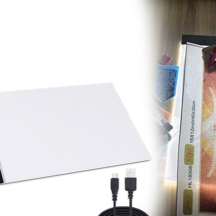 Light pad with cables and a small artwork on a wooden surface