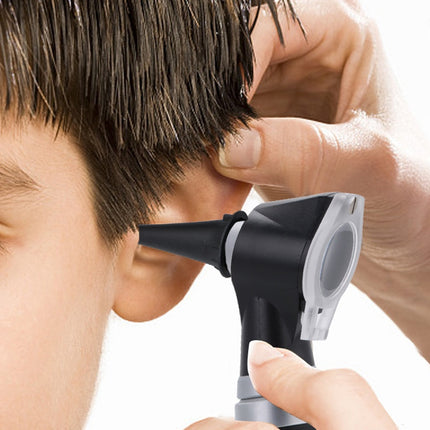 A close-up of a person using a black and silver otoscope to examine another person's ear against a white background.