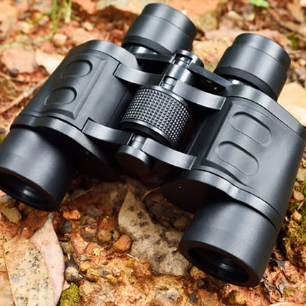 Black binoculars on a natural background with leaves and stones.