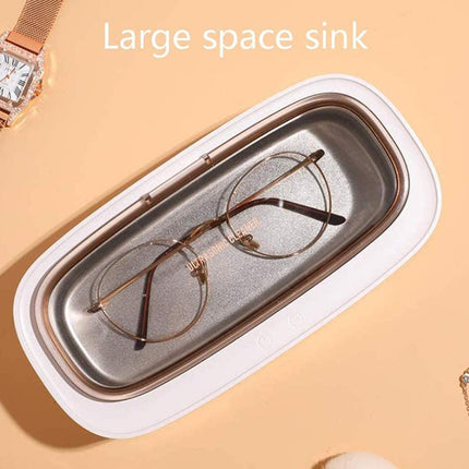 A large white and metallic silver space sink tray holding a pair of round metal-framed eyeglasses, shown on a peach background with a watch and necklace partially visible at the edges. Text at the top reads 'Large space sink'.
