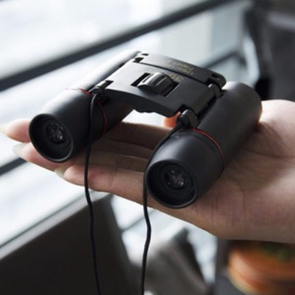 Black binoculars held in a hand with a blurred background