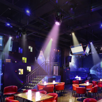 Interior of a nightclub with red chairs, tables, and stage lights.