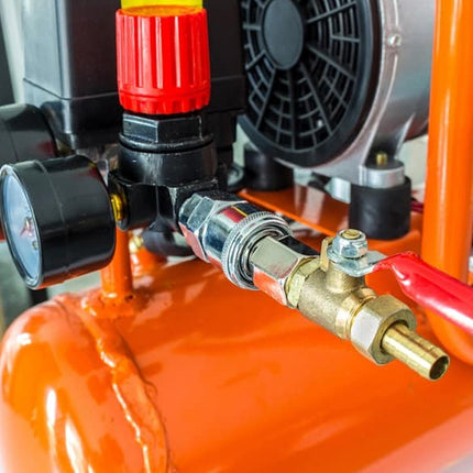 Close-up of an orange air compressor with visible gauges and valve.