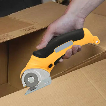 A hand holding a yellow and black utility knife cutter over a brown cardboard box.