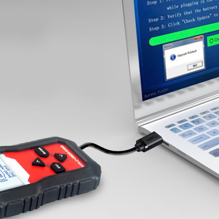 Black diagnostic tool connected to a laptop on a light gray surface