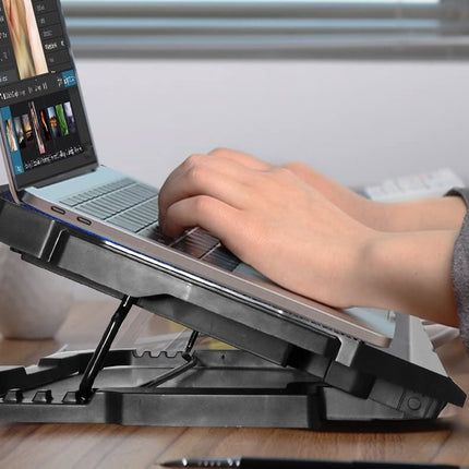 Person using a laptop on a black adjustable stand with a blurred background