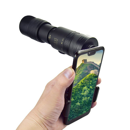 Hand holding a smartphone with a camera lens attached, displaying a scenic view.