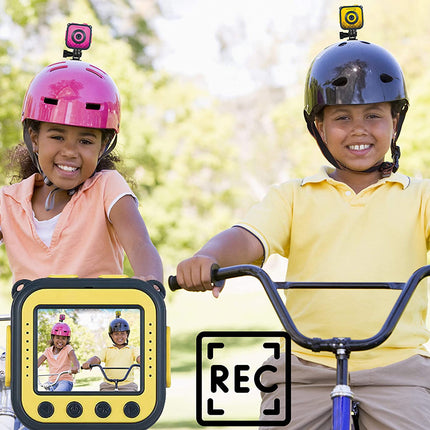 Two children riding bicycles outdoors, each wearing a helmet with a mounted camera that appears to record video. A large yellow camera mockup and a 'REC' overlay are shown in front of the children, indicating a product demonstration in a real outdoor setting.
