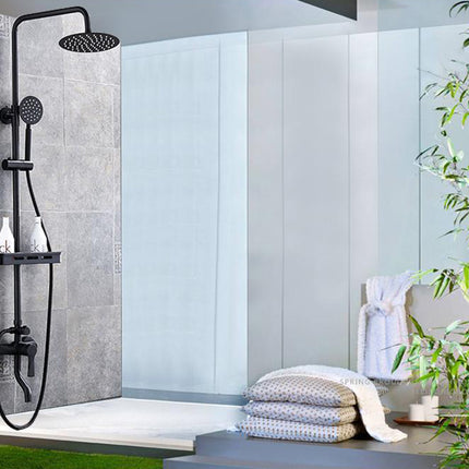 Modern shower setup with black shower head and controls in a bathroom.