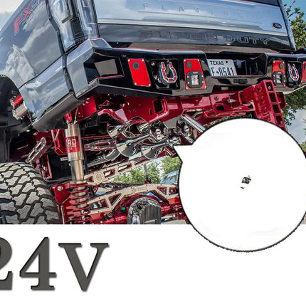 A close-up of a custom lifted black Ford truck with a detailed red suspension and exhaust system, featuring a circular inset showing a small black electronic component labeled 24V.