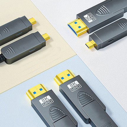 Four gray HDMI 2.0 extension cables with yellow and blue connector tips are arranged diagonally on a split cream and light blue background.