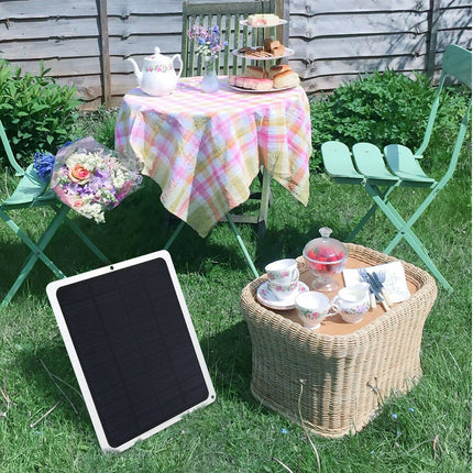 Outdoor setting with a table, chairs, and a solar panel on grass.
