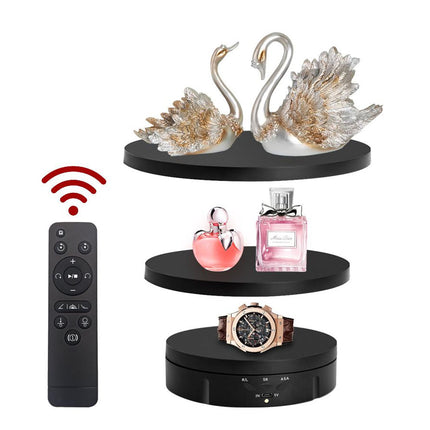 Black tiered display stand with decorative items including a remote control, swan figurines, perfume bottles, and a watch.