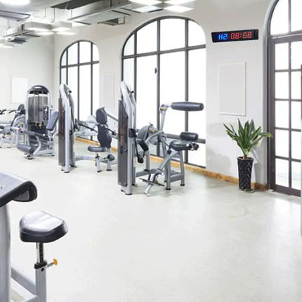 Gym interior with various exercise machines and large windows.