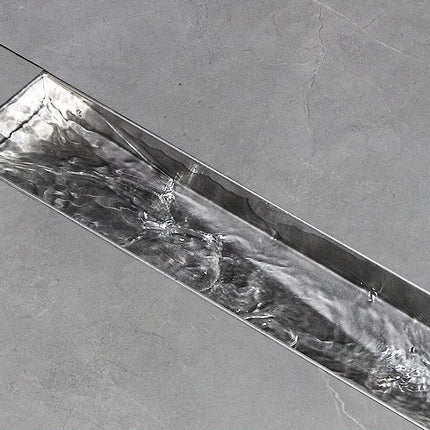 Close-up of a metallic strip with a textured surface on a gray background