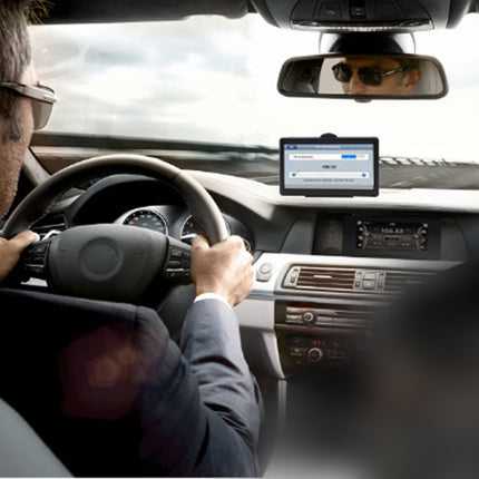 Person driving a car with a navigation device on the dashboard.