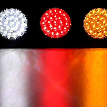 Three circular LED light units shown against a black background, emitting white, red, and amber light, with the colored light reflections visible on a surface below.
