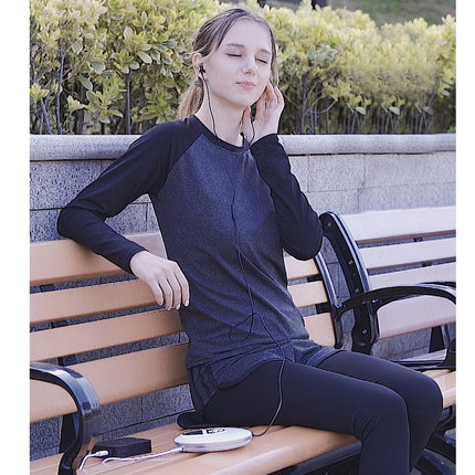 A woman sitting on a wooden park bench wearing a dark gray and black raglan long-sleeve athletic top and black leggings, with earphones in her ear.