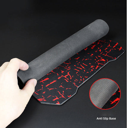 Hand holding a black textured mat with red patterns on a dark background