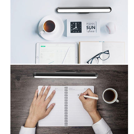 Person writing in a notebook at a desk with a cup of coffee, glasses, and a clock.