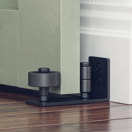 Close-up of a door stopper attached to a door frame with a wooden floor.